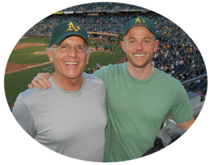 Attorney father and son, Stan and Nick Casper wearing baseball caps at baseball game