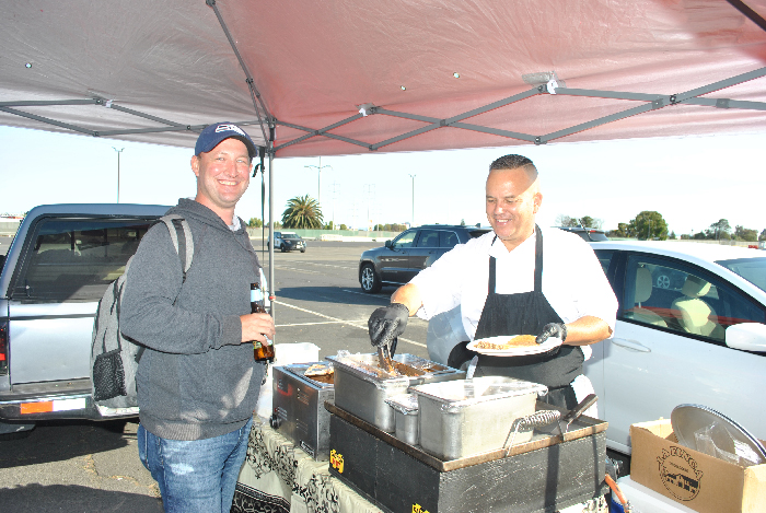 Abel Lopez of El Paisa Taqueria serves tacos before the A's game in July 2022