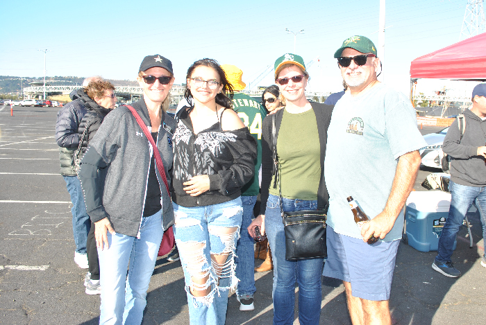 four happy A's fans at a tailgate barbecue before the game
