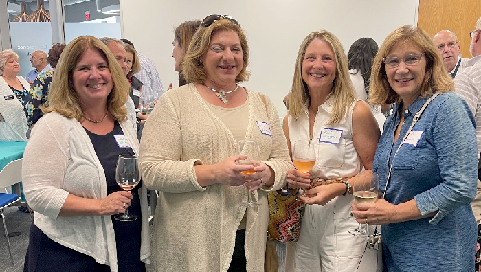 group of 4 women smiling, at cocktail party