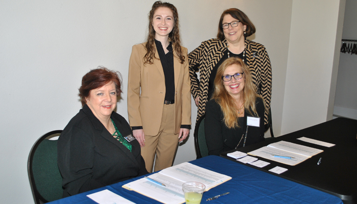 4 women smiling at check in table.