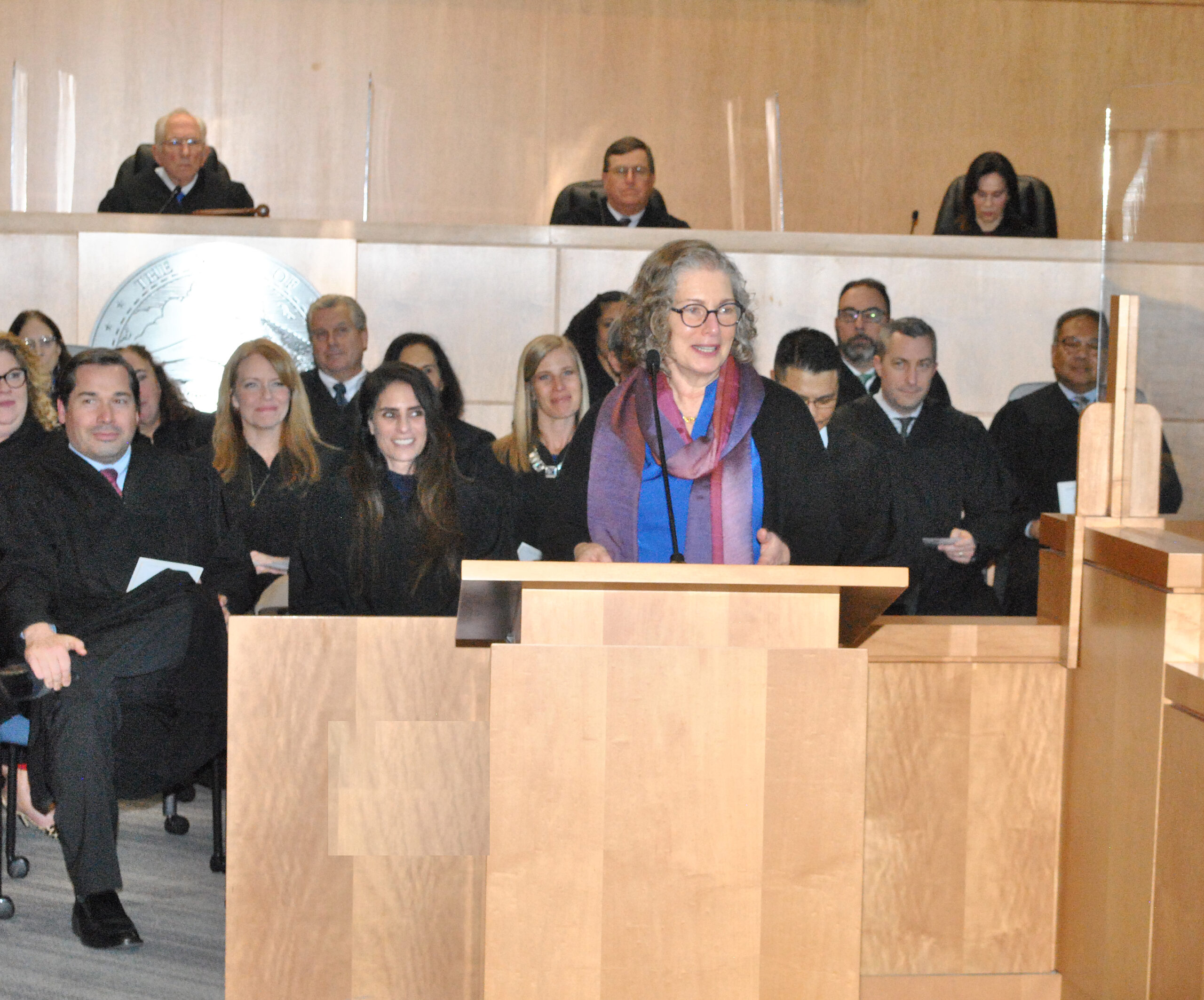 Woman speaks from podium in front of judges